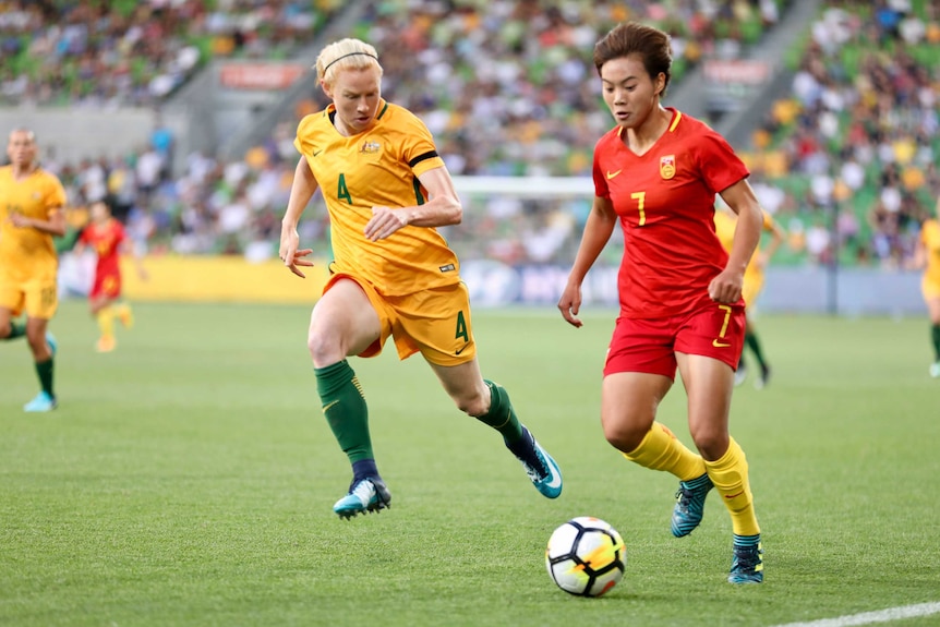 The Matildas' Clare Polkinghorne runs alongside a Chinese opponent during a match.