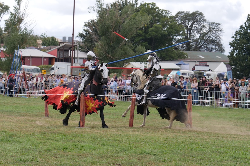 Two knights on horses jousting with large sticks 