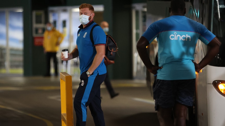 England cricketer Jonny Bairstow walks into the MCG holding a takeaway coffee cup and wearing a facemask.