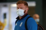 England cricketer Jonny Bairstow walks into the MCG holding a takeaway coffee cup and wearing a facemask.