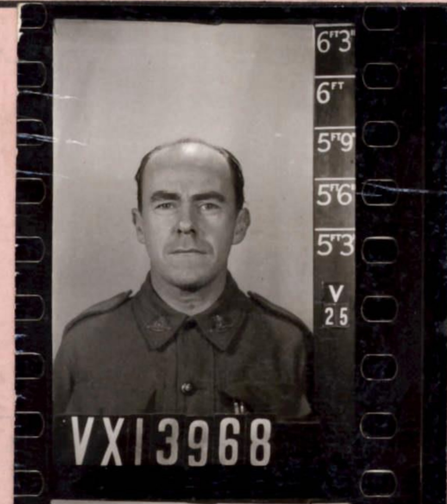 A man, bald on top, wears a military-style uniform.