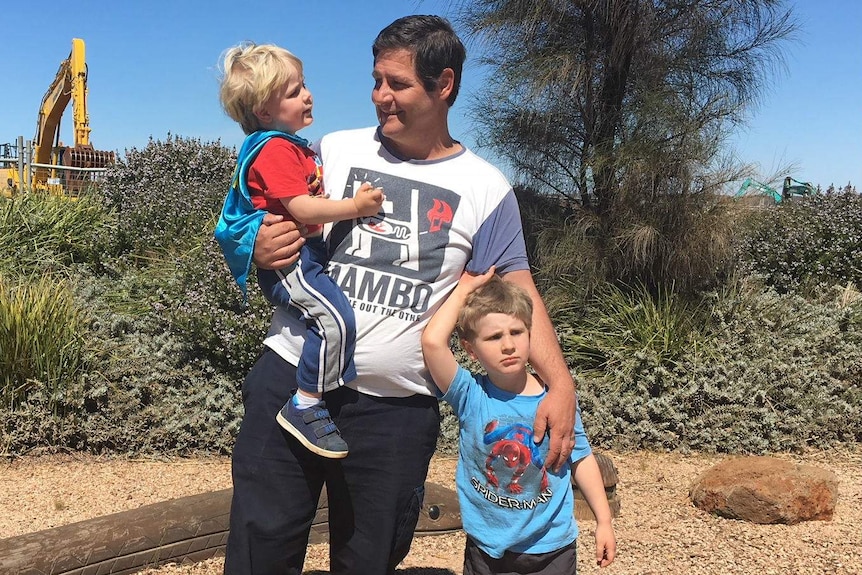 Larry Jarred looking at his son Kane while son Charlie stands beside him.