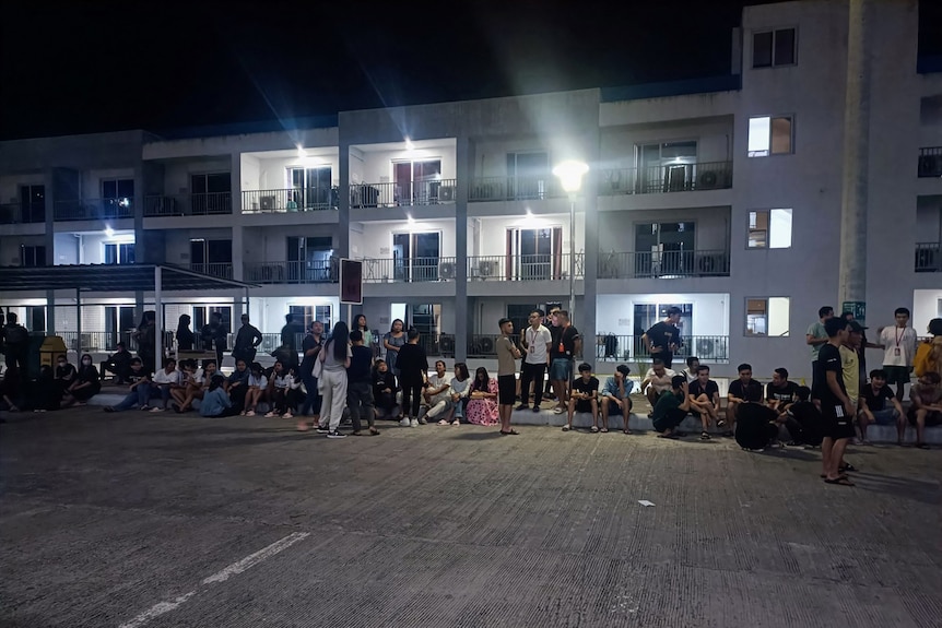A large group of people outside apartment buildings at night