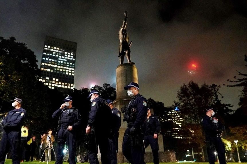 Police guard the Captain Cook statue in Sydney's Hyde Park at a Black Lives Matter protest.