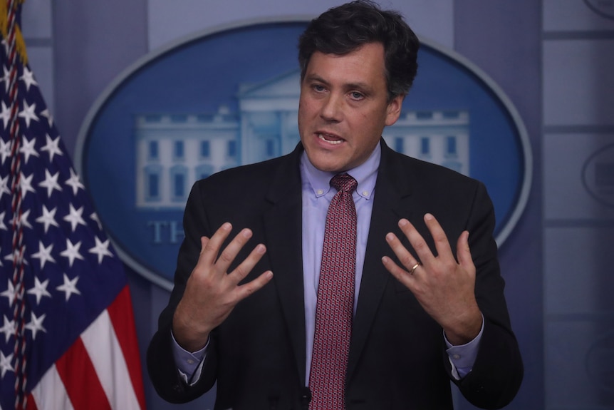 Man gesticulates at White House press room podium.