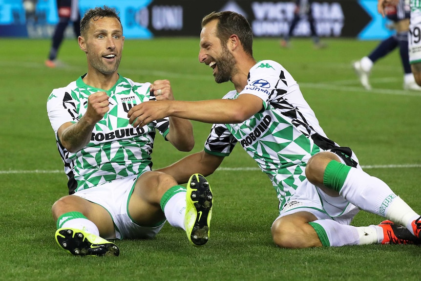Scott McDonald and Andrew Durante of Western United sit on the pitch and celebrate McDonald's match-winning goal.