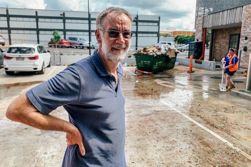 A man stands with hands on hips in a carpark of a furniture store