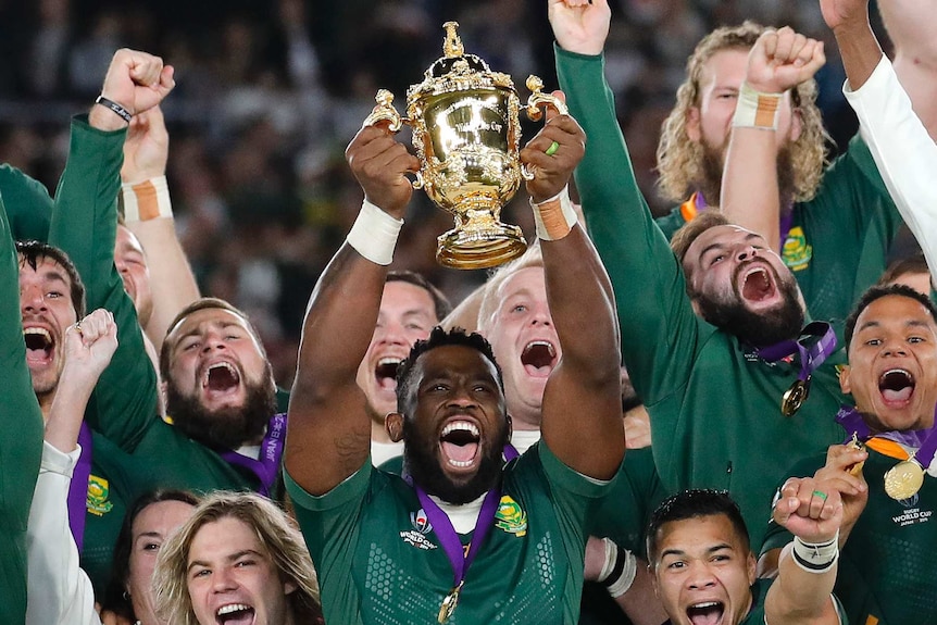 South Africa captain Siya Kolisi holds the Webb Ellis Cup up with teammates after the Rugby World Cup final.