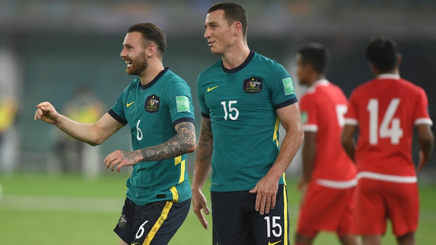  Mitch Duke and Martin Boyle celebrate wearing a dark green football kit