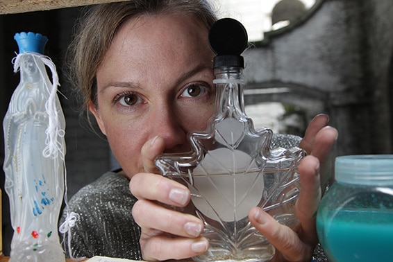 A photo of Amy Sharrocks holding a bottle from her Museum of Water collection.
