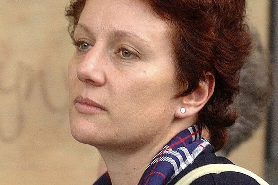A woman with short auburn hair looks wistfully off camera, to her left.