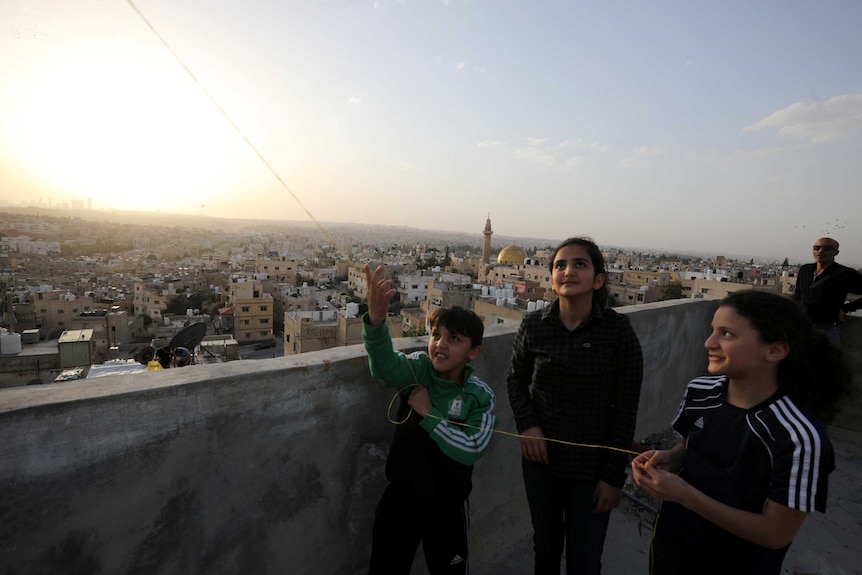 A group of children on a roof top in Amman flying a kite