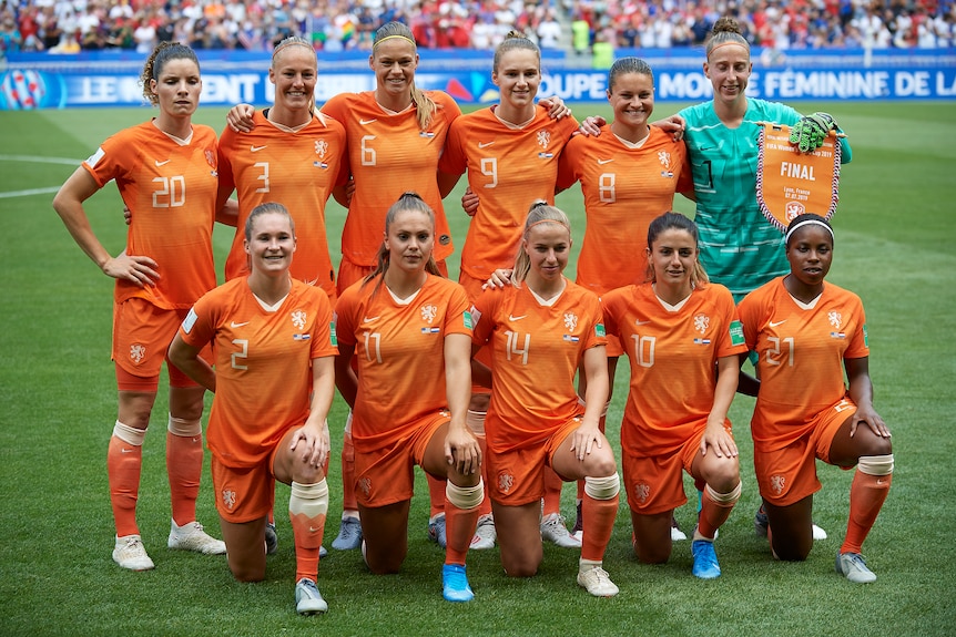 A women's soccer team wearing orange poses for a photo