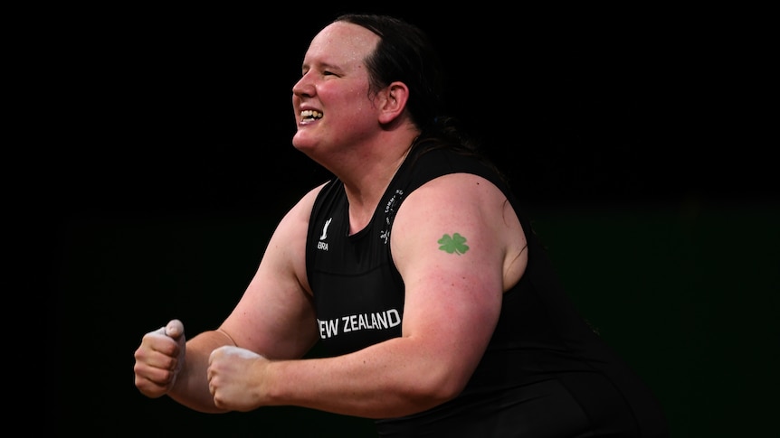 A transgender weightlifter smiles and pumps her fists in celebration after a lift at the Commonwealth Games