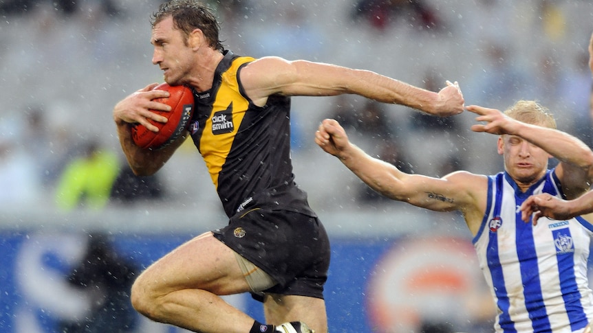 Shane Tuck breaking past Ben Warren carrying an AFL ball.