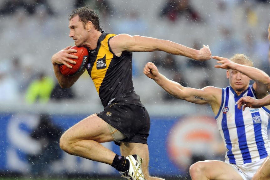 Shane Tuck breaking past Ben Warren carrying an AFL ball.