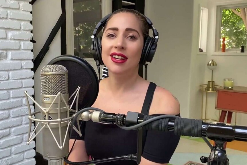 lady gaga wearing headphones and standing behind a microphone at her home