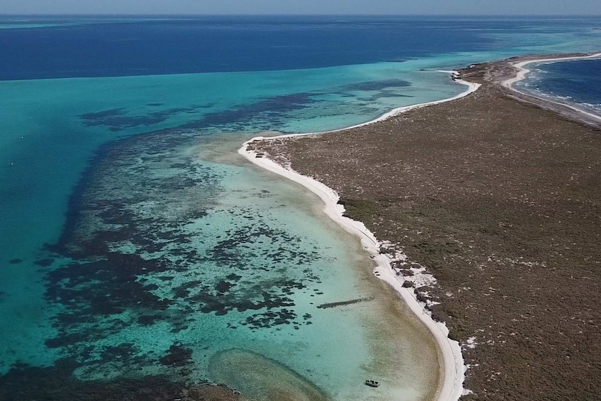 An aerial picture of a pristine beach and sparkling blue water