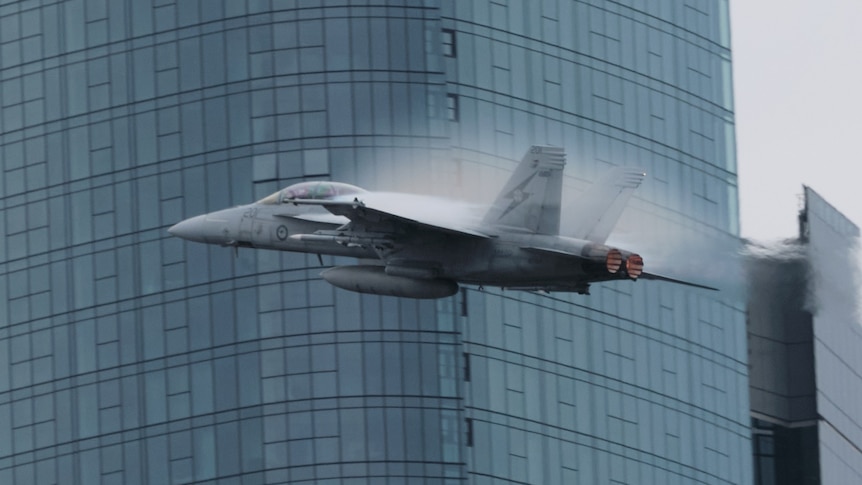 Close-up of F/A-18F Super Hornet flying through central Brisbane during a rehearsal, skyscrapers in background