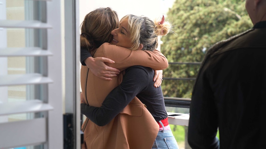 A woman hugs her friend as she enters a weekend barbeque, grateful for support and friendship as she prepares for an IUI attempt