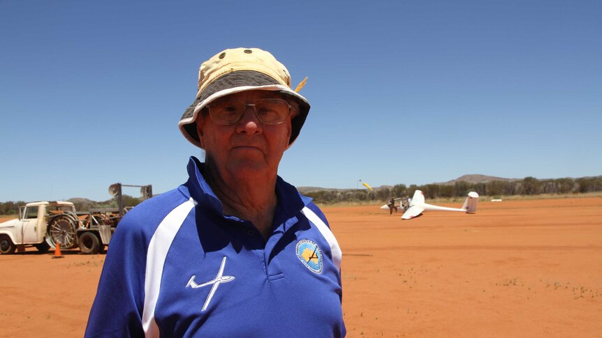 A man stands in front of a glider at Alice Springs.