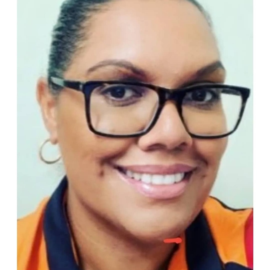 First Nations woman Letitia Kelly smiling at the camera wearing black glasses and an orange shirt