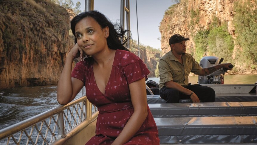 Miranda Tapsell sits on a boat in a gorge