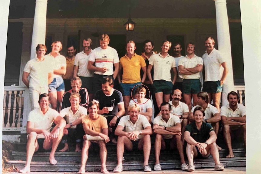 A group of more than 20 men in shorts and tshirts looking at the camera and smiling.