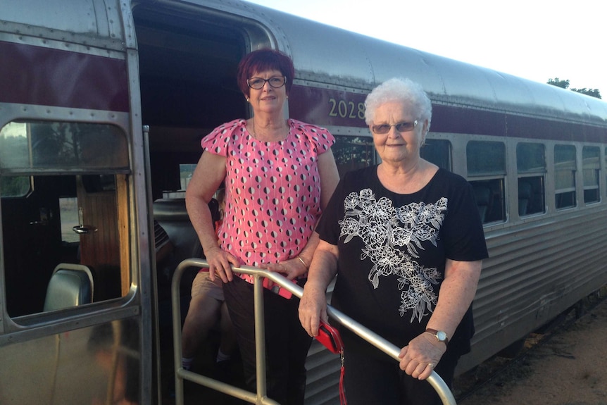 Two rural women pose in front of a train called the Savannahlander in Forsayth
