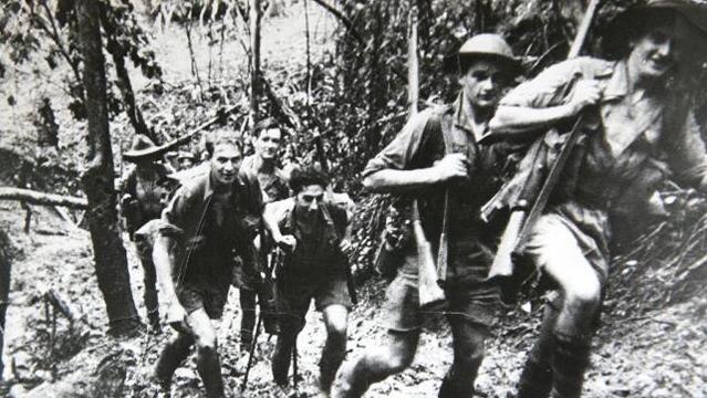 Old photo of soldiers walking along Kokoda Trail