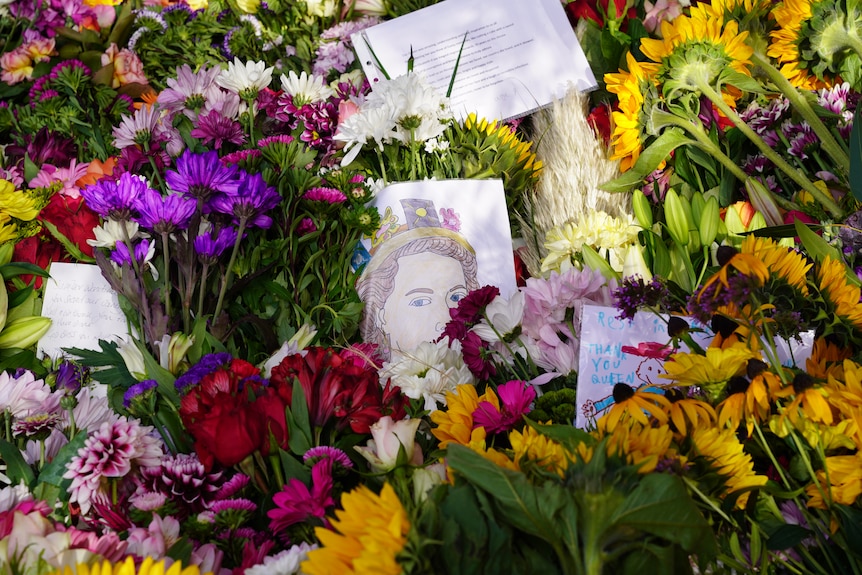 A close up shot of flowers with a drawing of the Queen. 