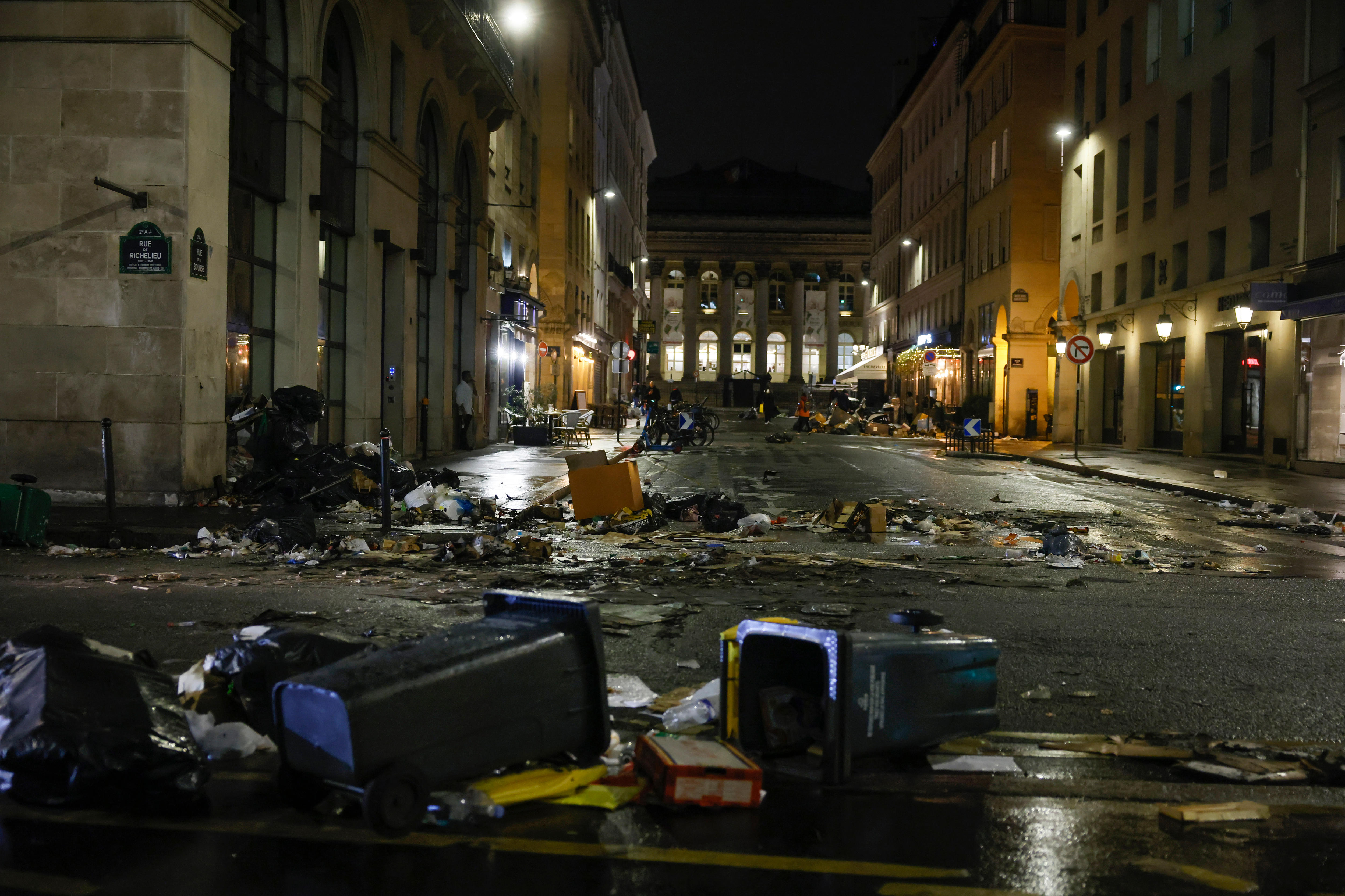 burnt garbage and bins are scattered across a street in Paris following riots