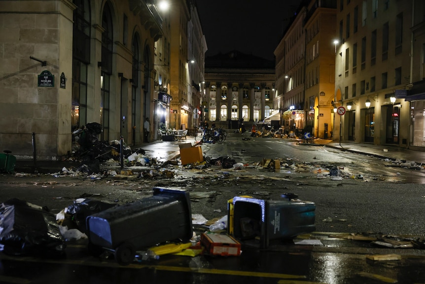 burnt garbage and bins are scattered across a street in Paris following riots