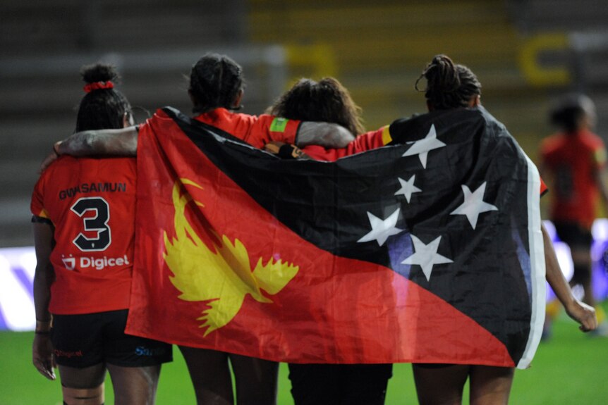 PNG Orchids players drape PNG flag over them after win RLWC
