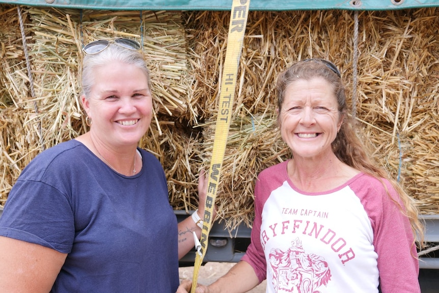 Two women smile with Hay behind them .