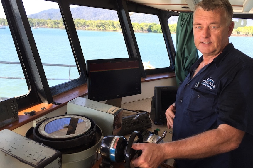 Fleet manager moves a trawler with the ocean, mangroves and mountains clearly visible through the wheelhouse windows