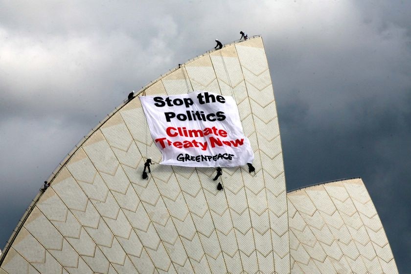 Activists on the Sydney Opera House hold a Greenpeace banner.