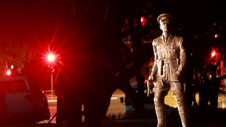 A bronze statue of Duncan Chapman is lit up in the darkness of the early morning.