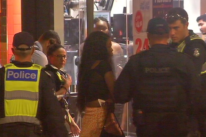 Police and members of the public stand outside a McDonald's on a dark morning.