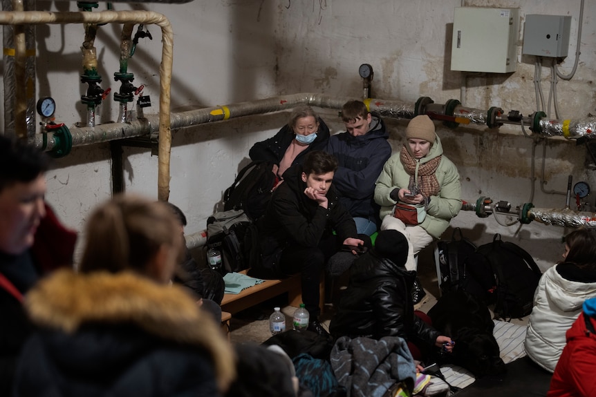 People shelter in the basement of a building in Kyiv, Ukraine, surrounded by the building's piping system.