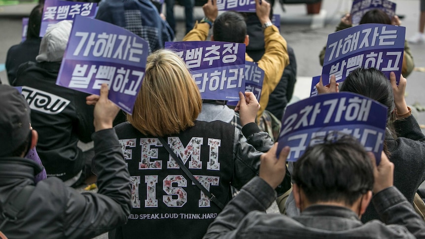 Protestors holding signs in Korean for feminist causes.