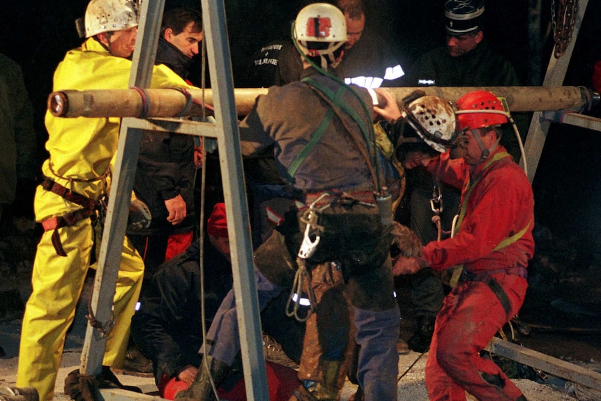 A man is hoisted above ground by rescuers using a temporary winch.