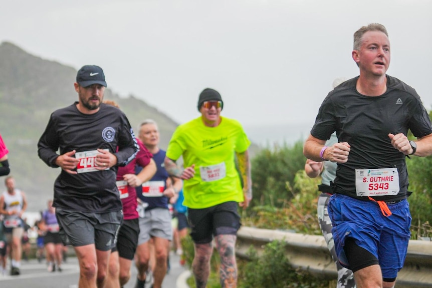 participants run along the great ocean road towards camera on a foggy day