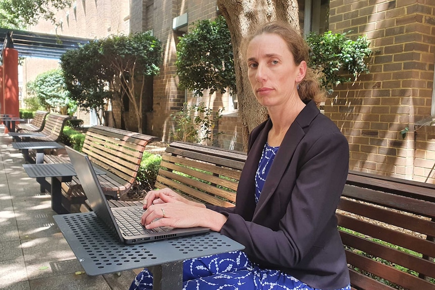 UNSW researcher Professor Fiona Johnston is tying on her laptop. She looks serious and wears a black blazer and dress.