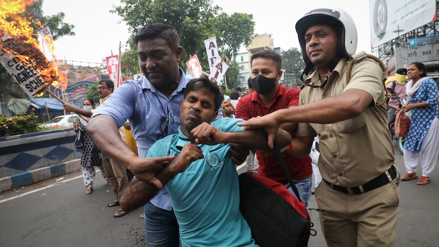 Three men struggle to restrain a protester.
