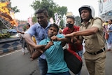 Three men struggle to restrain a protester.