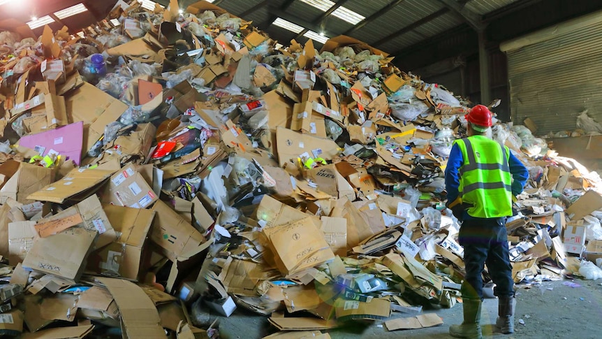 A worker inspects a pile of rubbish.