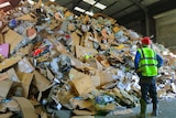 A worker inspects a pile of rubbish.