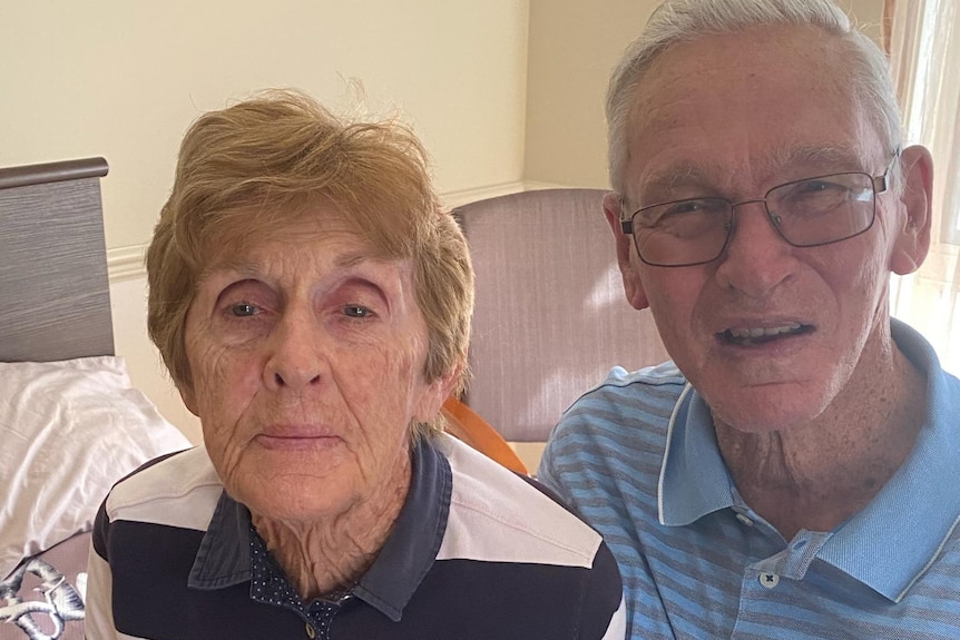 an elderly couple sitting on the bed