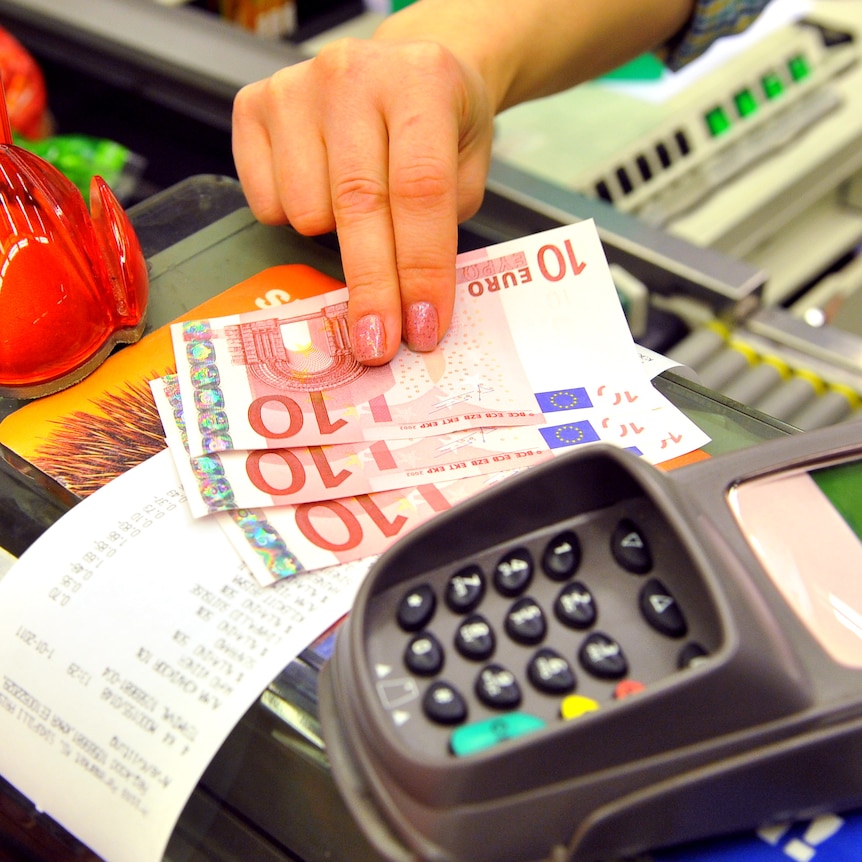 A Estonian woman gives change to a customer in Euro in a supermarket in Tallinn